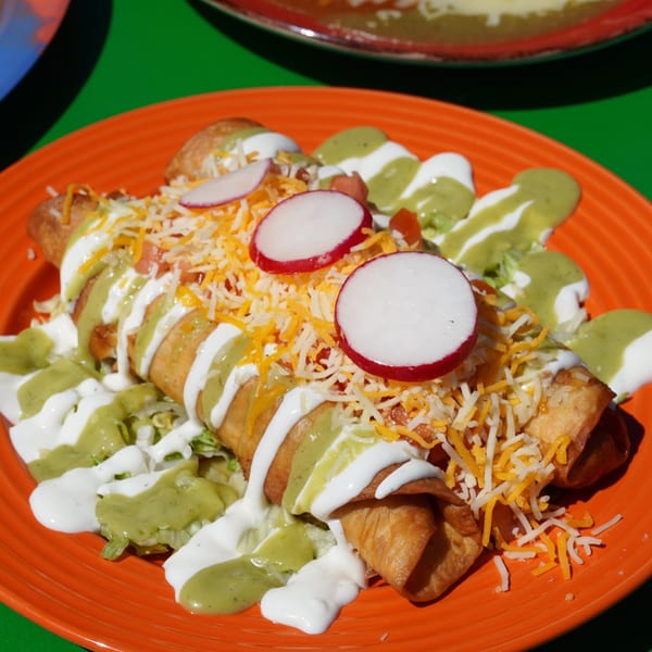 Loco Charlies' golden-fried flautas topped with shredded cheese, radishes, sour cream, and green sauce.