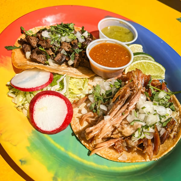 Two Loco Charlies tacos, one with beef and one with pork, served with salsa, limes, and radishes.