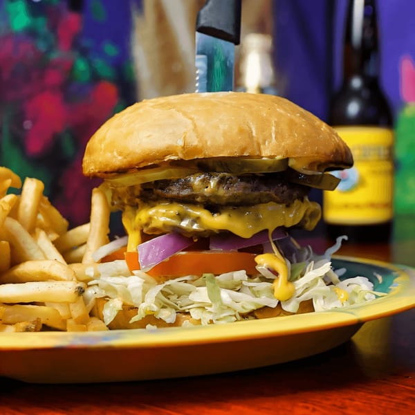 A double cheeseburger with lettuce, tomato, onion, and pickles, served with fries on a colorful plate.